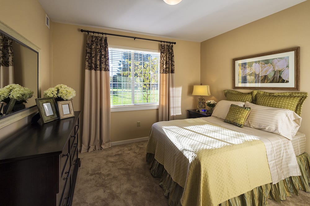 A well-decorated bedroom with a large window allowing natural light, complete with a cozy bed and stylish furnishings.