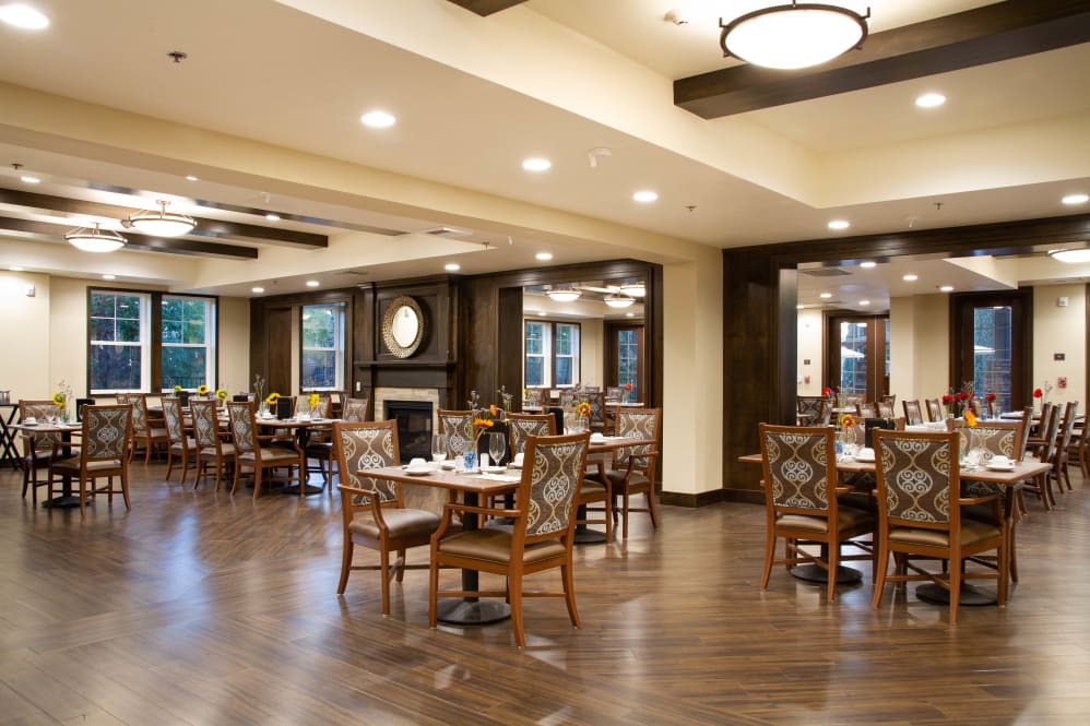 A cozy dining room with wooden flooring and well-arranged tables and chairs.