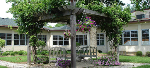 A serene garden setting featuring a pergola adorned with hanging flowers and comfortable seating.