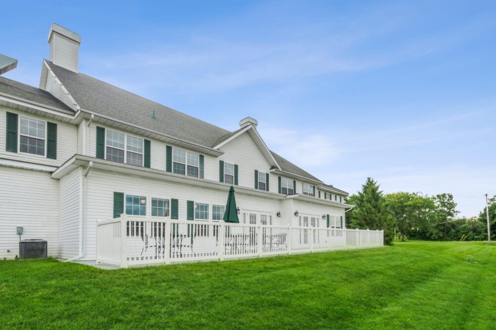 A large, white residential building with a green lawn and clear sky.