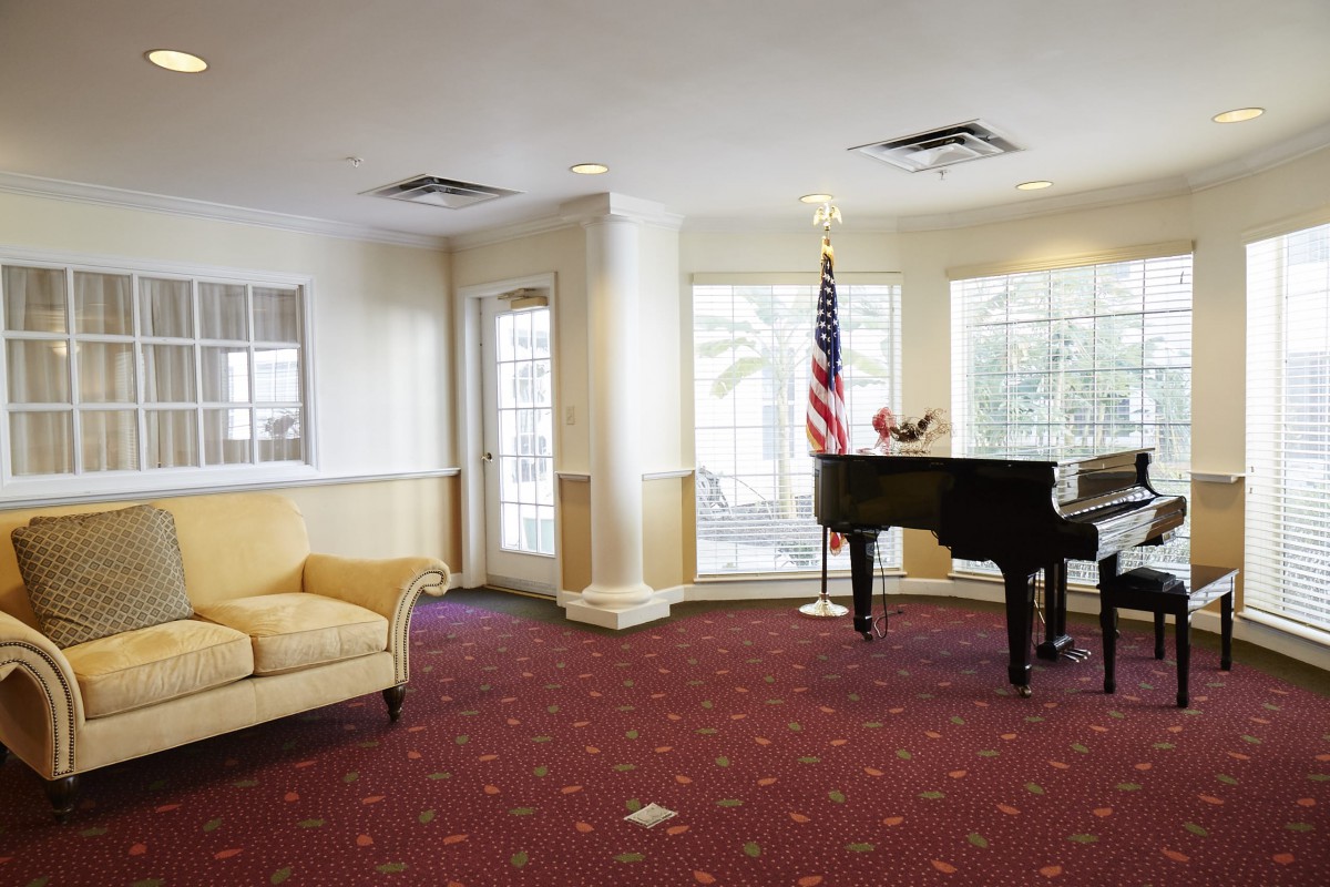 A well-furnished lobby area featuring a grand piano, sofa, and an American flag.