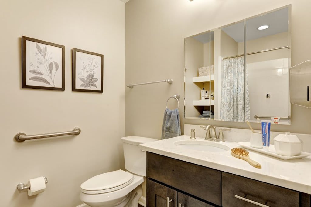 A modern bathroom with a sink, mirror, and toilet.