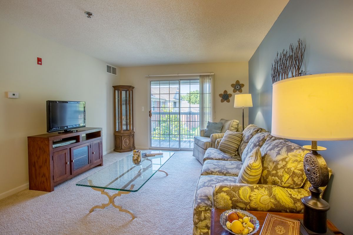 A cozy living room with a TV and glass coffee table.