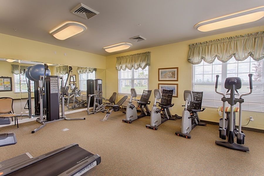 A well-equipped fitness room featuring stationary bikes and a treadmill, with mirrors and windows for a bright workout environment.