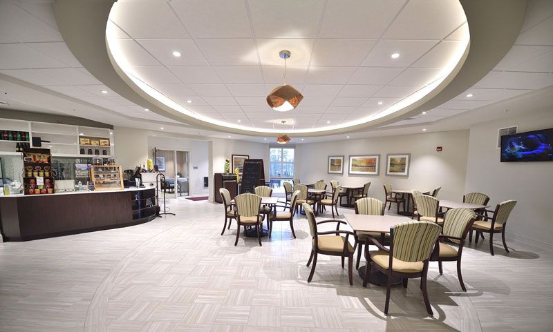 A modern dining area with arranged tables and chairs, featuring overhead lighting.
