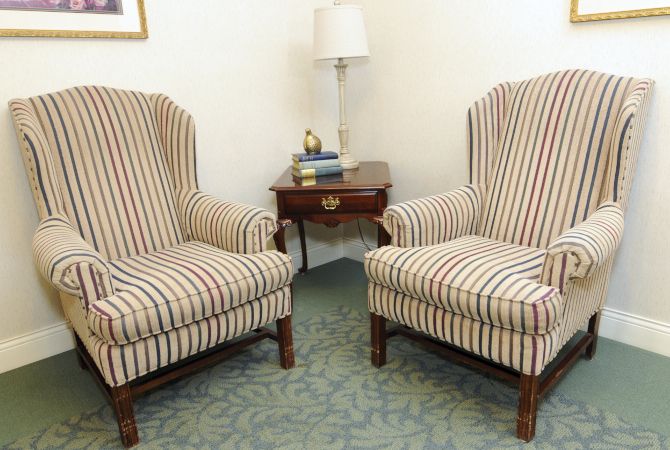 A cozy living room setup featuring two striped armchairs and a small wooden side table with a lamp.