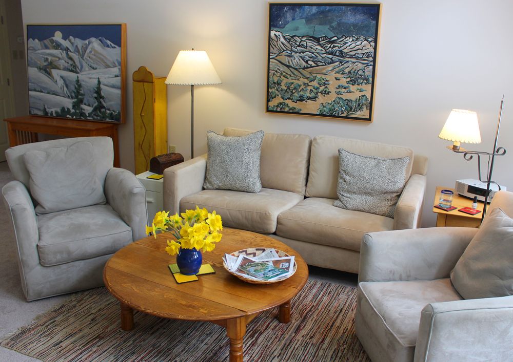 Cozy living room with a sofa, armchairs, and a coffee table adorned with yellow flowers.