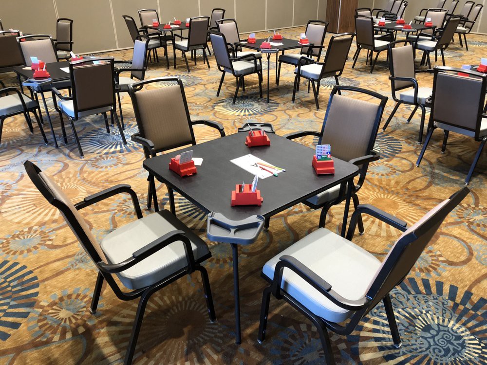 A room set up for a bridge card tournament with tables and chairs arranged neatly.