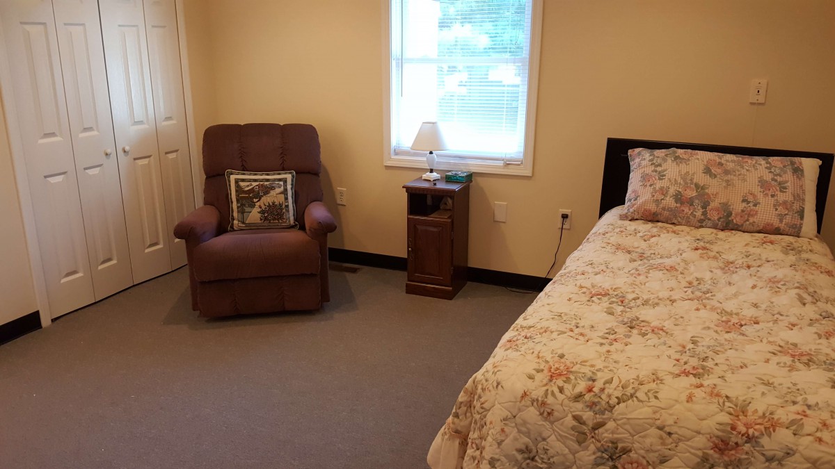 Cozy bedroom with a recliner chair, bedside table, and a window.