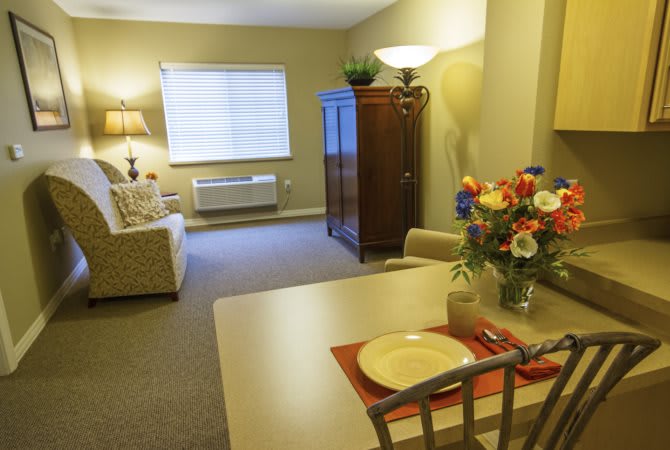 A cozy living room with a sofa, table setting, and decorative elements like flowers and lamps.