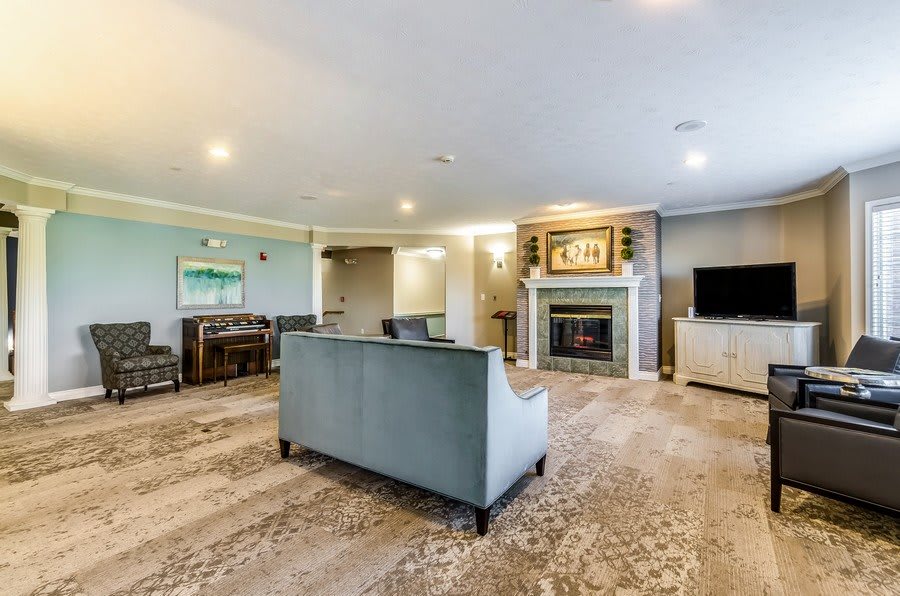 A spacious living room featuring a modern sofa, a cozy fireplace, and a television.