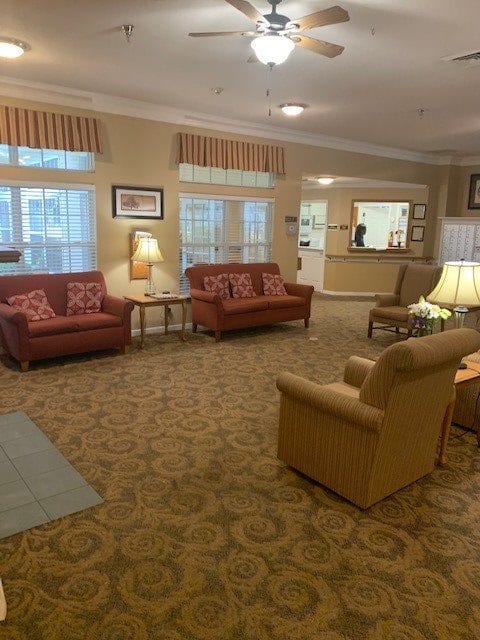 A cozy living room with sofas, chairs, and warm lighting.