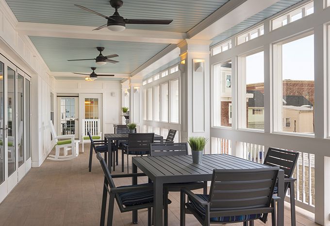 A modern outdoor patio dining area with tables and ceiling fans.