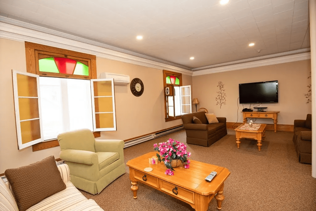 A cozy living room featuring comfortable seating, a wooden coffee table with a floral centerpiece, and a wall-mounted television.