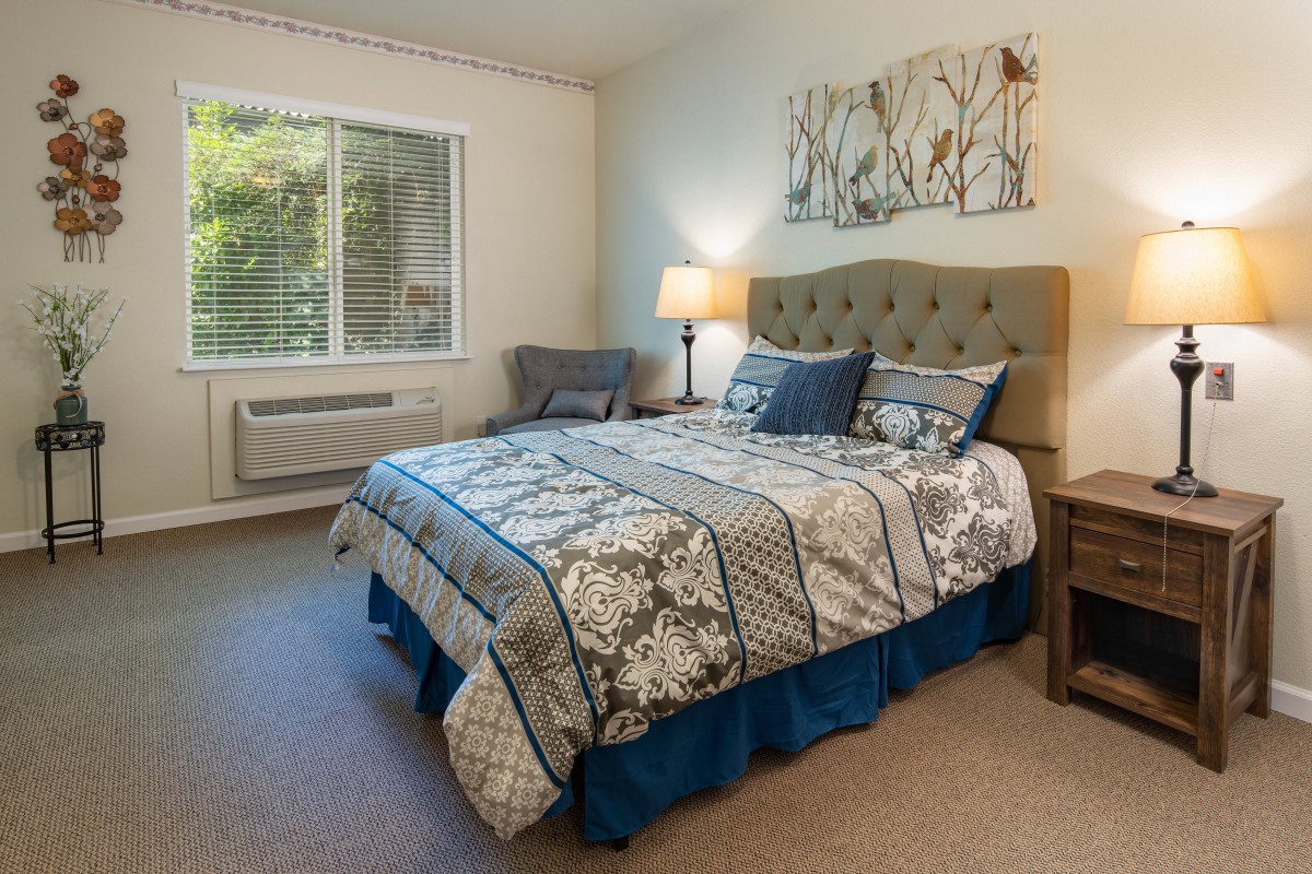 A cozy bedroom with a neatly made bed and warm lighting.
