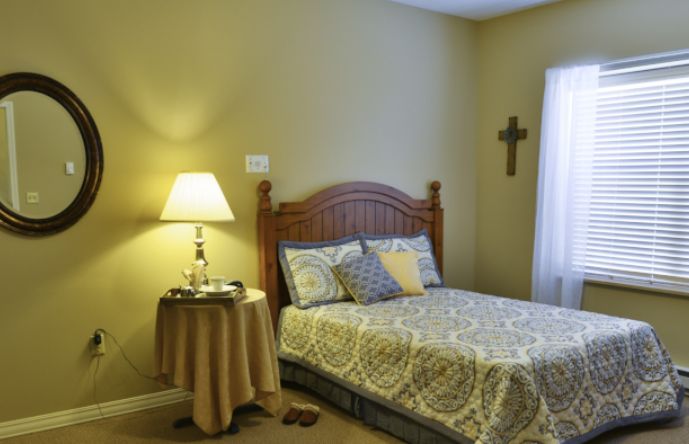 A cozy bedroom with a wooden bed frame, patterned bedspread, and a lamp on the nightstand.
