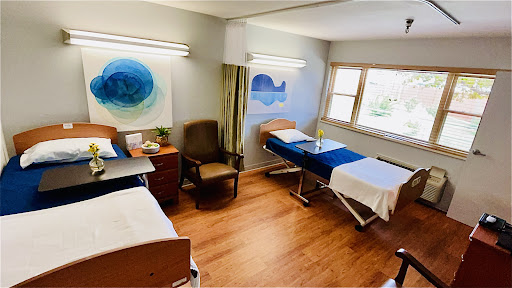 A bright and inviting hospital room designed for patient comfort, featuring two beds and cheerful artwork.