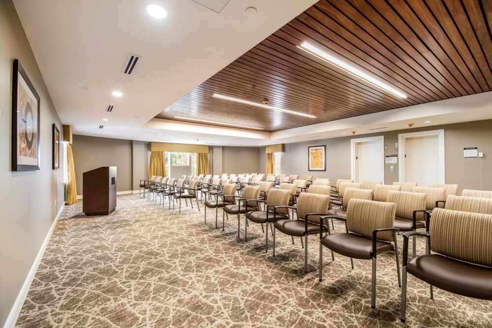 A modern conference room with neatly arranged chairs and a podium.