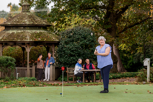 A group of seniors enjoys a day of golfing and socializing in a beautiful garden setting.