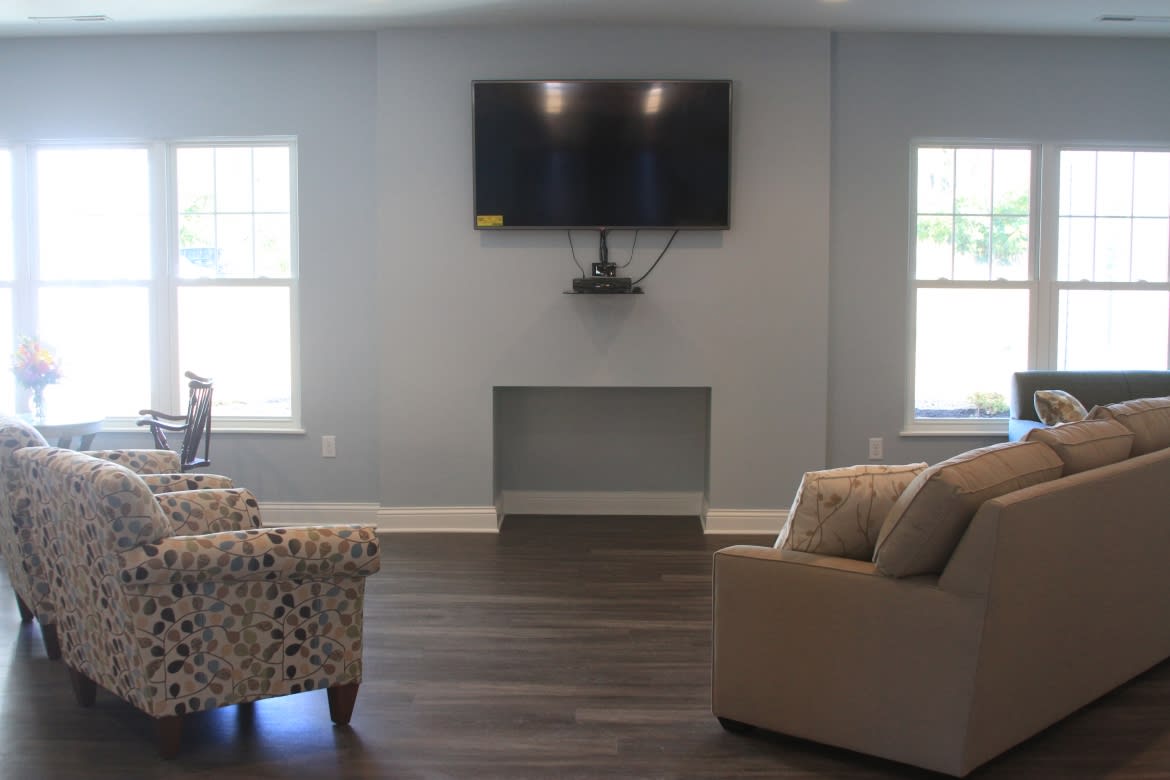 A cozy living room with a mounted television and comfortable seating.