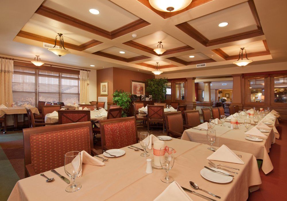 A warmly lit restaurant interior with set tables and chairs awaiting guests.