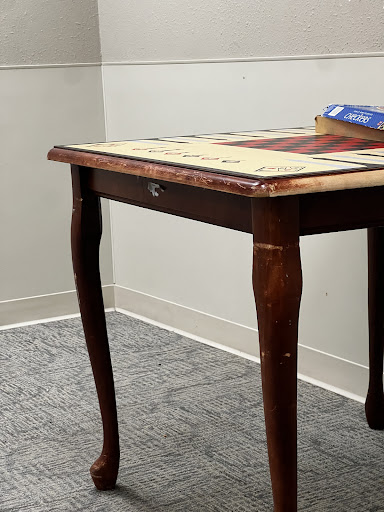A close-up of a rustic wooden table with a patterned top and a book resting on it.