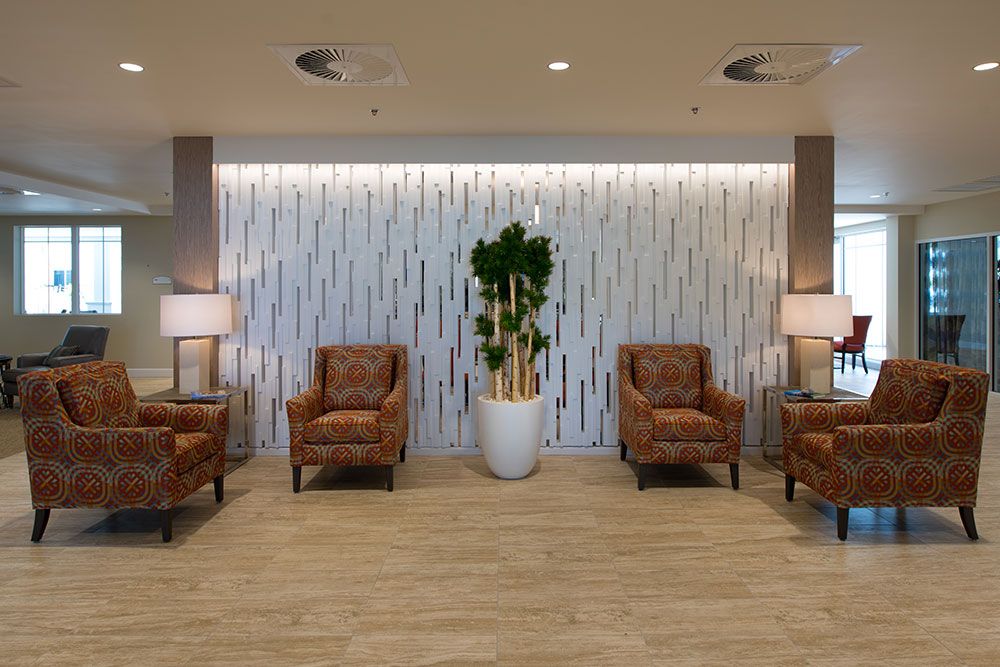 A modern lobby seating area with upholstered chairs, a decorative plant, and ambient lighting.