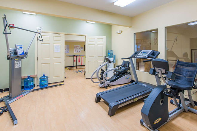 A small gym with exercise equipment including a treadmill and an elliptical machine.