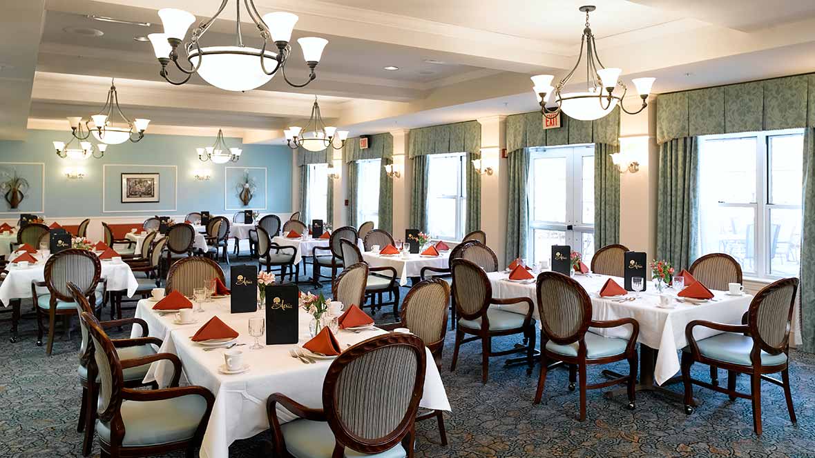 An elegant dining room with neatly arranged tables and chairs, featuring chandeliers and a sophisticated atmosphere.