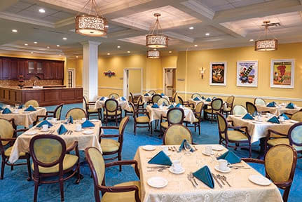 An elegant dining room with neatly arranged tables and chairs, featuring a warm color scheme.