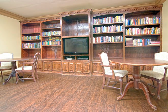 A cozy home library with wooden bookshelves, a television, and comfortable chairs.