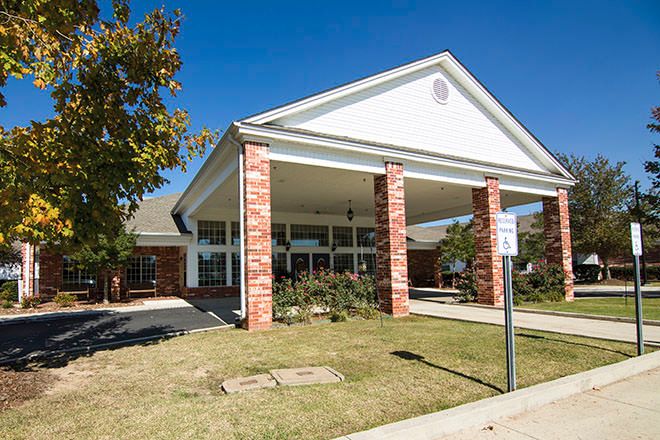 A brick-pillar entrance of a building with a covered driveway on a sunny day.