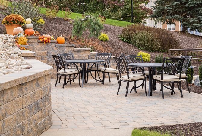 A well-designed patio with outdoor seating, surrounded by autumn-themed landscaping and pumpkins.