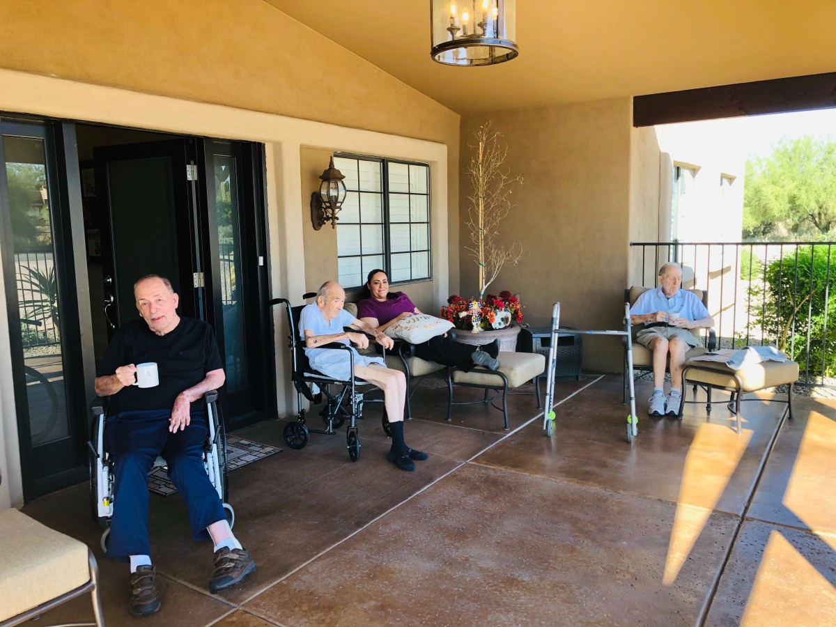 A group of elderly people sitting on a porch, enjoying a relaxing daytime conversation.