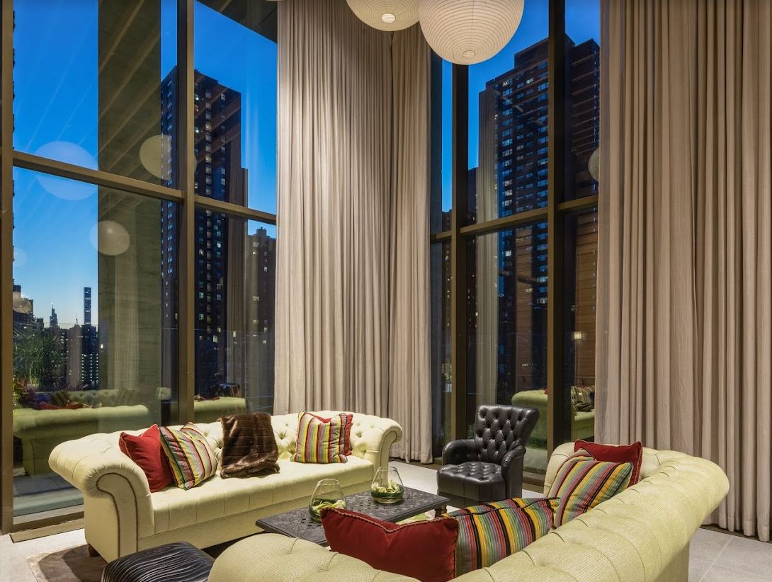 A luxurious living room with a modern design and large windows showcasing a cityscape view at dusk.