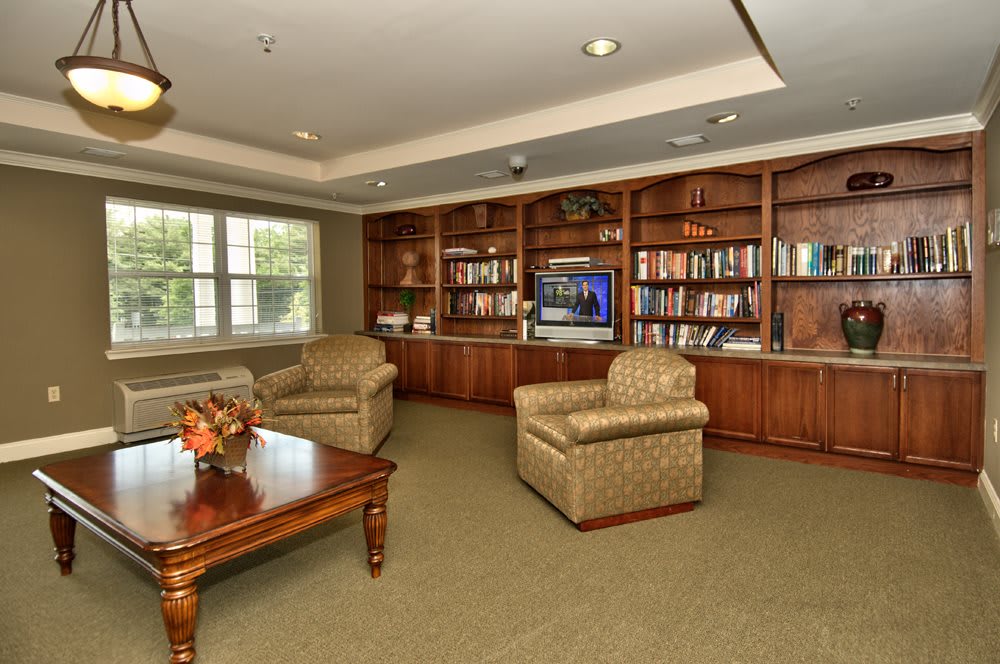 A cozy living room with a library, featuring bookshelves, armchairs, and a coffee table.