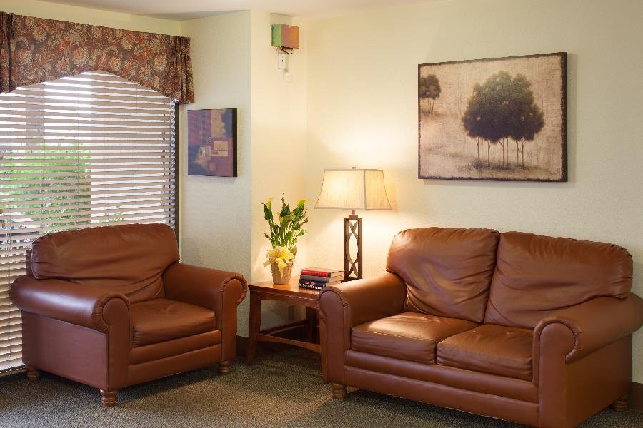 A cozy living room with leather sofas, a lamp, and framed artwork on the walls.