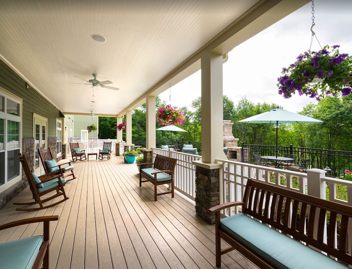 A spacious covered porch with wooden benches and hanging plants, perfect for relaxation.