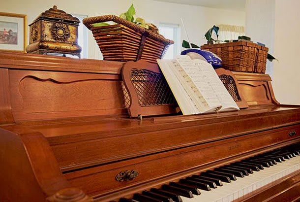 A wooden piano adorned with sheet music and decorative baskets.
