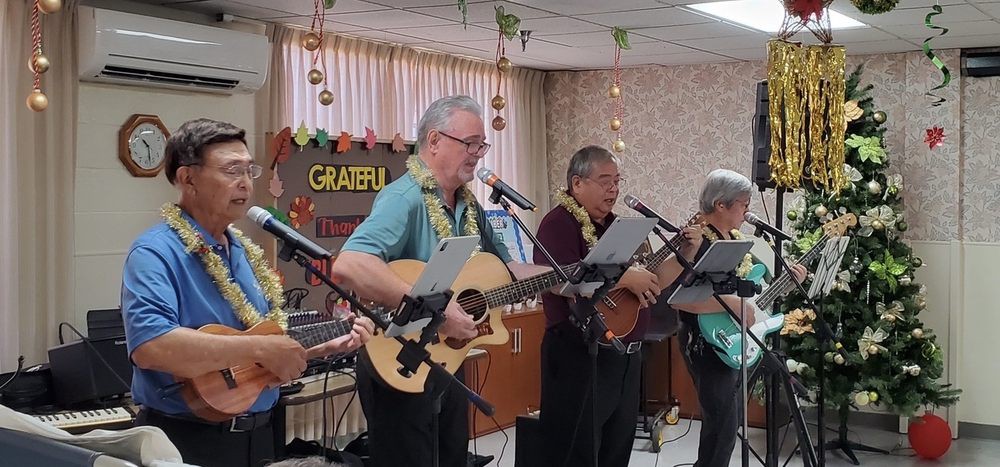 A group of musicians performing with guitars and ukuleles on stage.