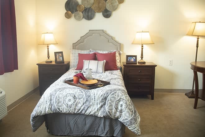 A cozy bedroom with a neatly made bed, flanked by two nightstands and lamps.