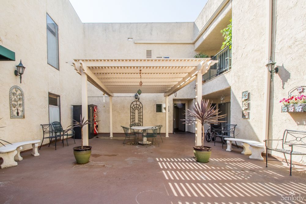 A spacious courtyard featuring a pergola with outdoor seating and potted plants.