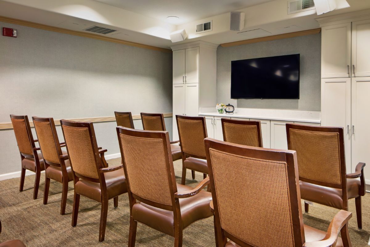 A small conference room with arranged chairs facing a large television.