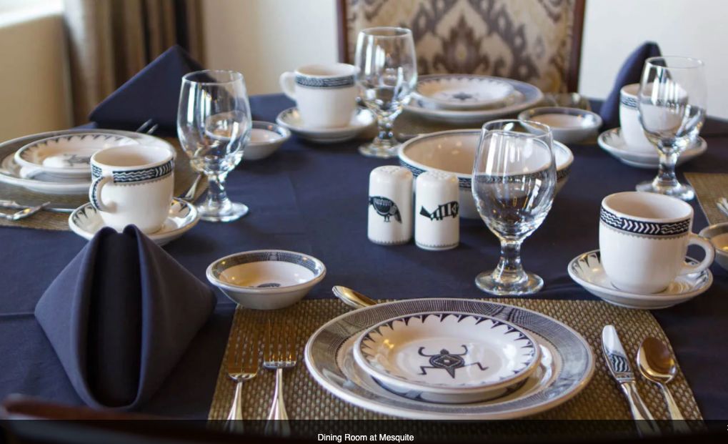 Elegantly set dining table with plates, glassware, silverware, and neatly folded napkins.