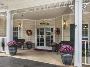 A welcoming hotel entrance adorned with floral arrangements and benches.