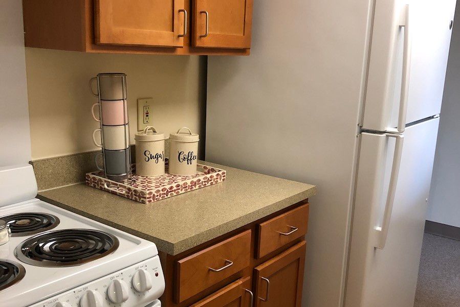 Cozy kitchen corner with wooden cabinets, a stove, and decorative canisters on the countertop.