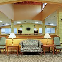 A comfortable seating area in a well-lit lobby with a sofa, chairs, and lamps.