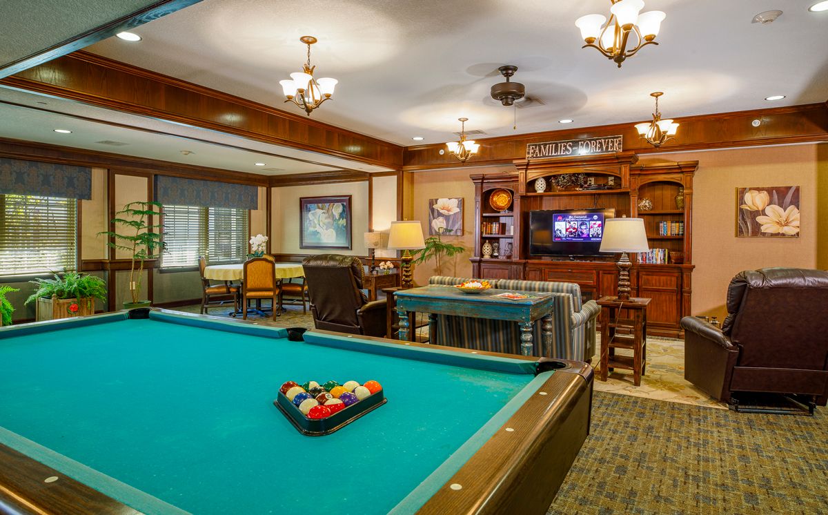 A cozy game room featuring a billiards table, comfortable seating, and a television.