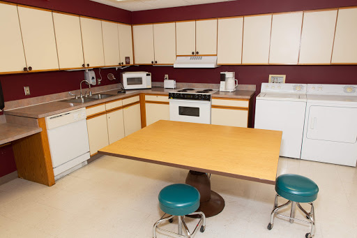 A cozy kitchen with a wooden table and teal stools, featuring essential appliances.