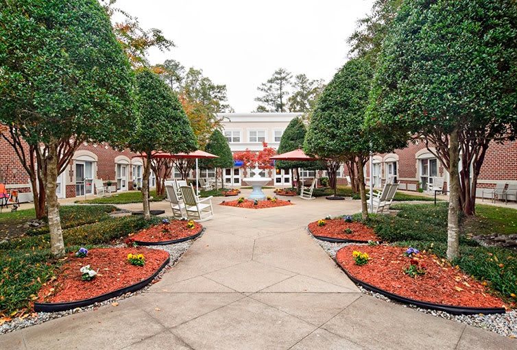 An elegantly landscaped garden with a central pathway leading to a stately building.